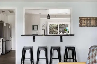 a kitchen with four bar stools in front of a counter at O-Side Beach Bungalow with Jaccuzi Blocks to beach in Oceanside
