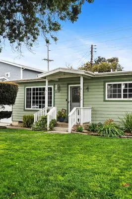 a green house with a white porch and a yard at O-Side Beach Bungalow with Jaccuzi Blocks to beach in Oceanside