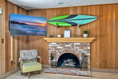 a living room with a fireplace with a green umbrella on the wall at Hot Tub, Fire Pit, BBQ, Shuffleboard, Walk To Beach in Carlsbad