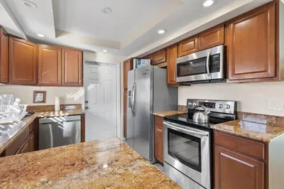 a kitchen with stainless steel appliances and wooden cabinets at Ocean Song in San Diego
