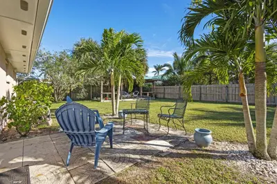 a yard with three chairs and palm trees at Ocean Song in San Diego
