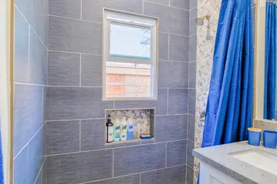 a bathroom with a gray tiled shower with a window at 2BR Retreat Near Balboa Park in San Diego