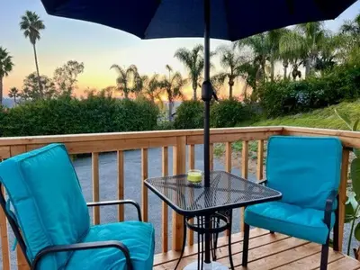 two chairs and a table with an umbrella on a deck at Tiny House on private large property in Vista