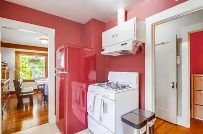 a kitchen with red walls and a white stove at Sunny San Diego Golden Hill Home! Pet Friendly, near DT, Fully Stocked! in San Diego
