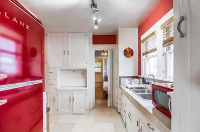 a kitchen with white cabinets and red walls at Sunny San Diego Golden Hill Home! Pet Friendly, near DT, Fully Stocked! in San Diego