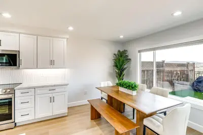 a kitchen and dining room with white cabinets and a wooden table at Balconies and Views Modern Abode in Poway! in Poway