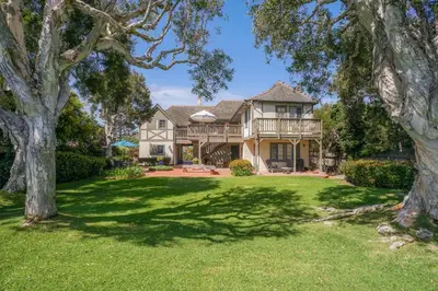 a house with a large yard with trees at Gated Lakefront Estate - Seaside with Private Beach in Oceanside