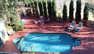 a swimming pool with benches and chairs and trees at Autumn Room at Eaglenest Inn with Pool and SPA in Julian