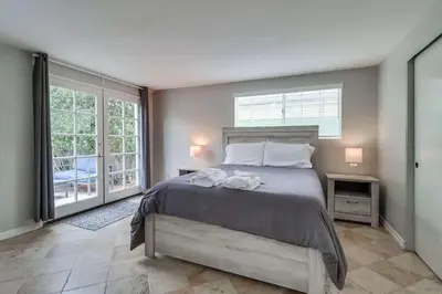 a bedroom with a large bed and two windows at Half block to bay steps to ocean AC large patio in San Diego