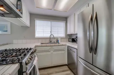 a kitchen with white cabinets and a stainless steel refrigerator at Steps to bay & ocean Belmont Park dining in San Diego