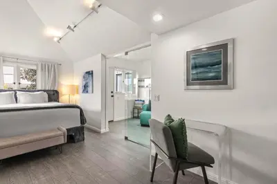 a bedroom with a bed and a chair and a mirror at Chic La Jolla Studio Steps to Ocean & Dining in San Diego