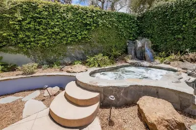 a hot tub in a garden with stairs around it at La Jolla Shores Perfection with Hot Tub, Fence Yard, AC & Grill in San Diego