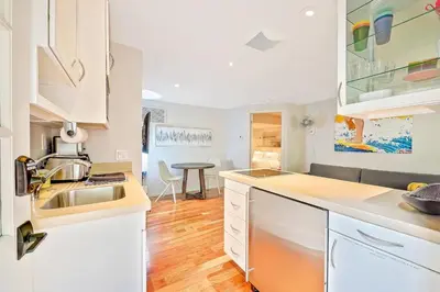 a kitchen with white cabinets and a sink and a table at La Jolla Shores Perfection with Hot Tub, Fence Yard, AC & Grill in San Diego