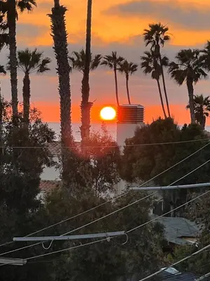 a sunset with palm trees and the ocean at Close to Ocean and Beach in San Diego