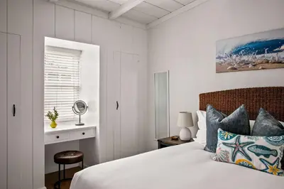 a white bedroom with a bed and a window at Beautiful Windansea Beach Compound Steps to Sand in San Diego