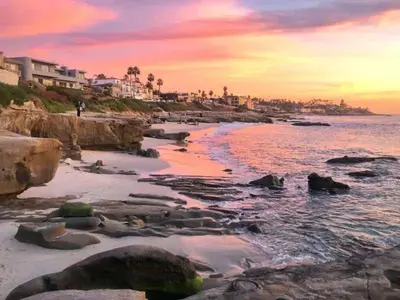 a beach with rocks and the ocean at sunset at Seaside 1BR Steps to Windansea Beach & Peek Views in San Diego