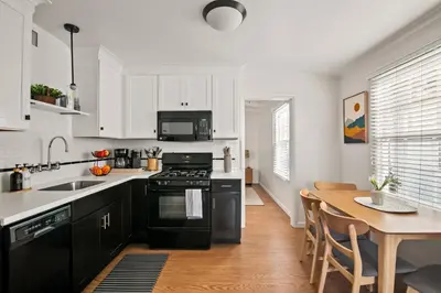 a kitchen with black appliances and a wooden table at Seaside 1BR Steps to Windansea Beach & Peek Views in San Diego