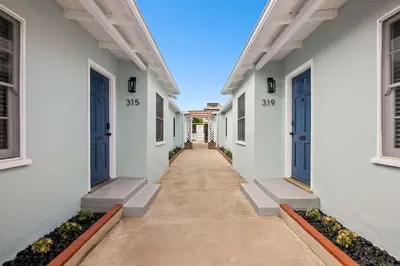 a hallway of white houses with blue doors at Beachside 1BR Haven Near Ocean & Outdoor Space in San Diego