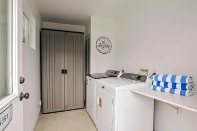 a white laundry room with a washing machine and a clock at Beachside 1BR Haven Near Ocean & Outdoor Space in San Diego