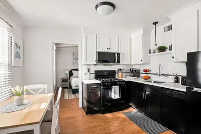 a kitchen with white cabinets and black appliances at Beachside 1BR Haven Near Ocean & Outdoor Space in San Diego