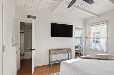 a white bedroom with a bed and a flat screen tv at Beachside 1BR Haven Near Ocean & Outdoor Space in San Diego