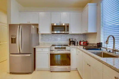 a kitchen with white cabinets and stainless steel appliances at 1 Mi to Heritage Lake Park Duplex with Patio! in Menifee