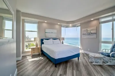 a bedroom with a bed and a chair and windows at 901 S Pacific in Oceanside