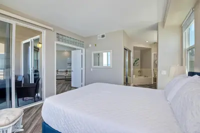 a bedroom with a large white bed and a living room at 901 S Pacific in Oceanside