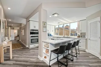 a kitchen with white cabinets and black stools at 901 S Pacific in Oceanside