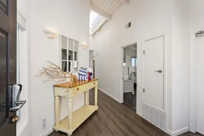 a hallway with white walls and a table and a door at 1317 S Pacific - Entire Home in Oceanside