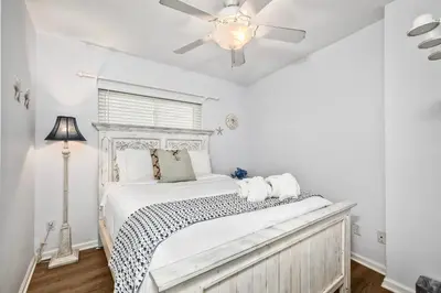 a bedroom with a white bed with a ceiling fan at 1409 S Pacific Street 5BR in Oceanside