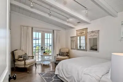 a white bedroom with a bed and two chairs at 3690 Carlsbad Boulevard - Entire Home in Carlsbad