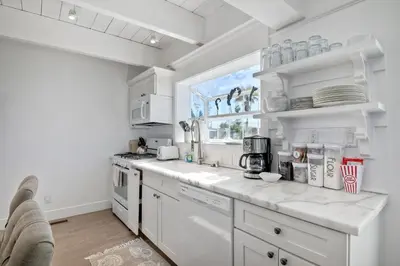 a white kitchen with white appliances and a window at 3690 Carlsbad Boulevard - Entire Home in Carlsbad