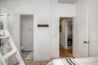 a white bedroom with a door leading to a bathroom at 180 n 190 Walnut Entire Home in Carlsbad