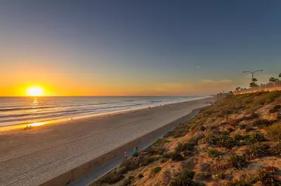 a beach at sunset with the sun setting over the ocean at 180 Walnut Upper in Carlsbad