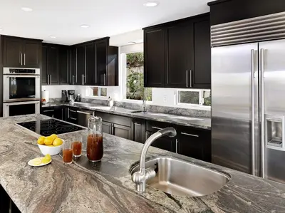 a kitchen with black cabinets and a stainless steel refrigerator at 327 Hillcrest Drive in Encinitas