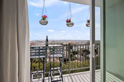 a balcony with two chairs and two potted plants at Majestic Mermaid Retreat in San Diego