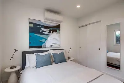 a white bedroom with a bed and a painting on the wall at Newly Renovated Pacific Beach Home with Private Yard and AC in San Diego
