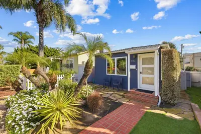 a home with palm trees and a blue door at Newly Renovated Pacific Beach Home with Private Yard and AC in San Diego