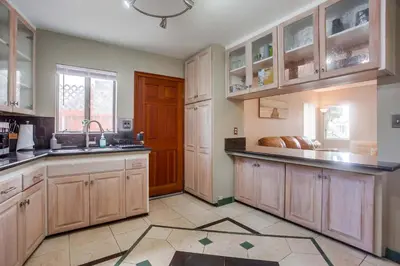 a large kitchen with wooden cabinets and a sink at Rooftop patio ocean views surf break steps away in San Diego