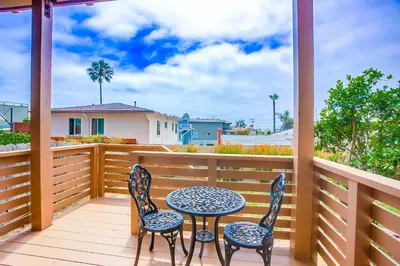 a patio with two chairs and a table on a balcony at Rooftop patio ocean views surf break steps away in San Diego