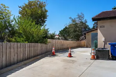 three orange traffic cones on a sidewalk in front of a fence at The Little Oasis in Escondido