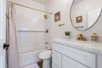 a white bathroom with a toilet and a mirror at The Little Oasis in Escondido