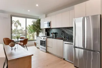 a kitchen with white cabinets and a stainless steel refrigerator at Ocean View Luxury Living in Carlsbad