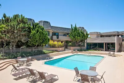 a swimming pool with chairs and a table next to a building at Coastal Heights - DMBC857C in Solana Beach