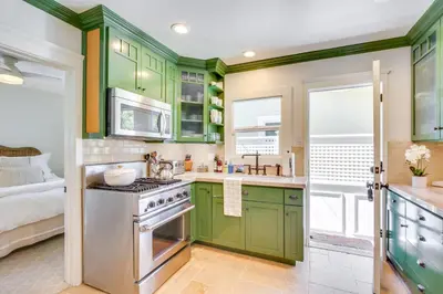 a kitchen with green cabinets and a sink at Walkable Cottage Near Balboa Park with Yard and Grill! in San Diego