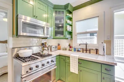 a kitchen with green cabinets and a stove at Walkable Cottage Near Balboa Park with Yard and Grill! in San Diego