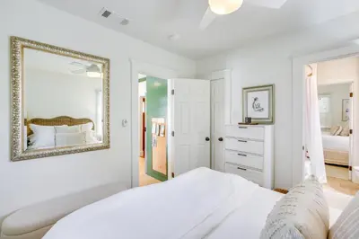 a white bedroom with a bed and a mirror at Walkable Cottage Near Balboa Park with Yard and Grill! in San Diego