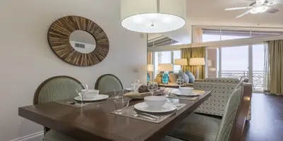 a dining room with a table with chairs and a mirror at Grand Pacific Palisades in Carlsbad