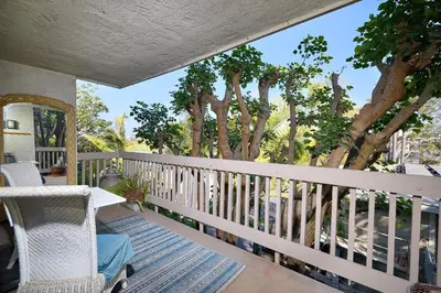 a white rocking chair on a porch with trees at Oceanside Beach Condos in Oceanside